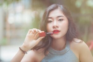 赤いリップを塗るおしゃれな若い女性